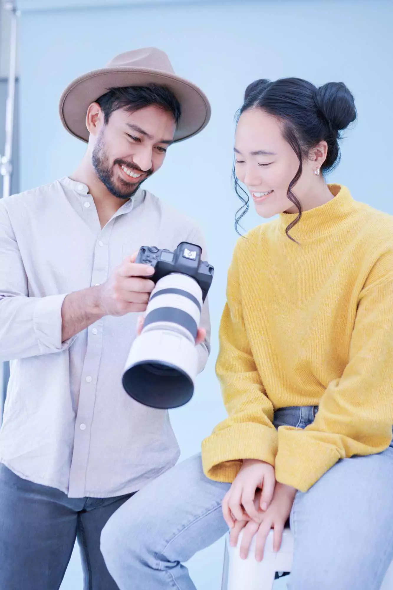 Photographe présentant un aperçu photo à une femme dans un studio lumineux.